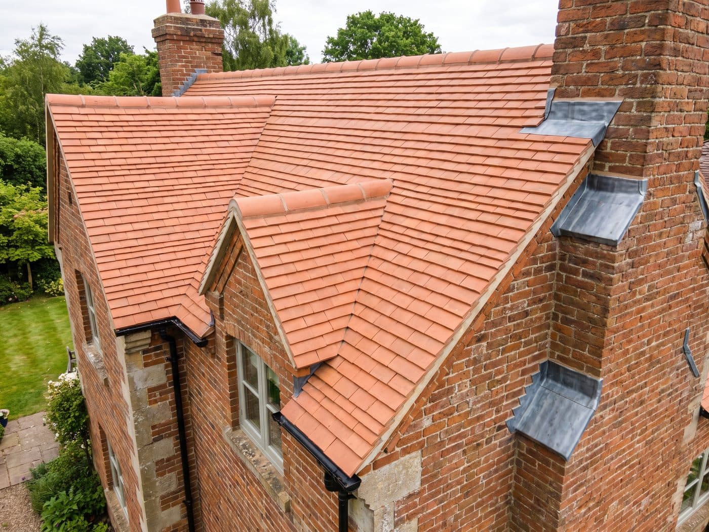 A newly completed clay tiled roof with even terracotta courses and a clean ridge line