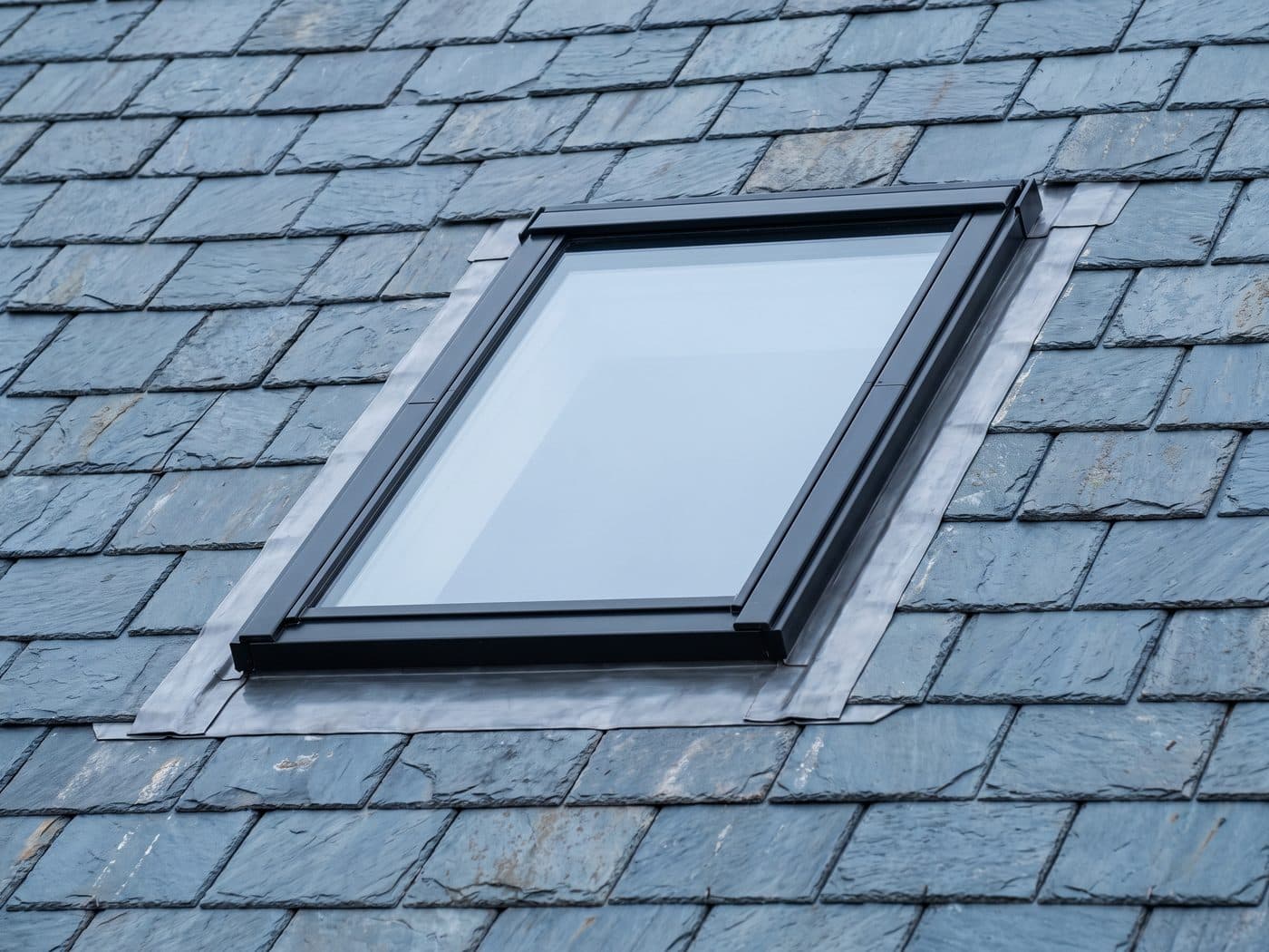 A flush conservation rooflight set into a slate roof with lead flashing dressed around it
