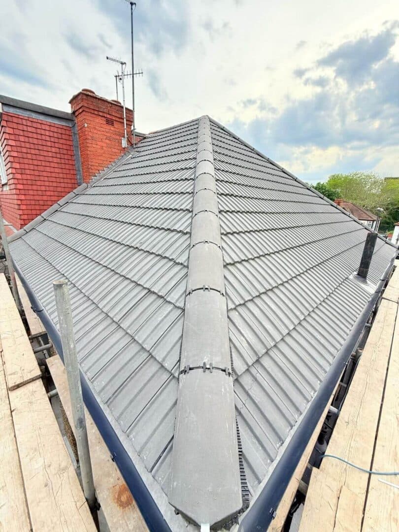 A grey interlocking tiled hip roof with dry-fix ridge and hips, scaffold boards along the eaves