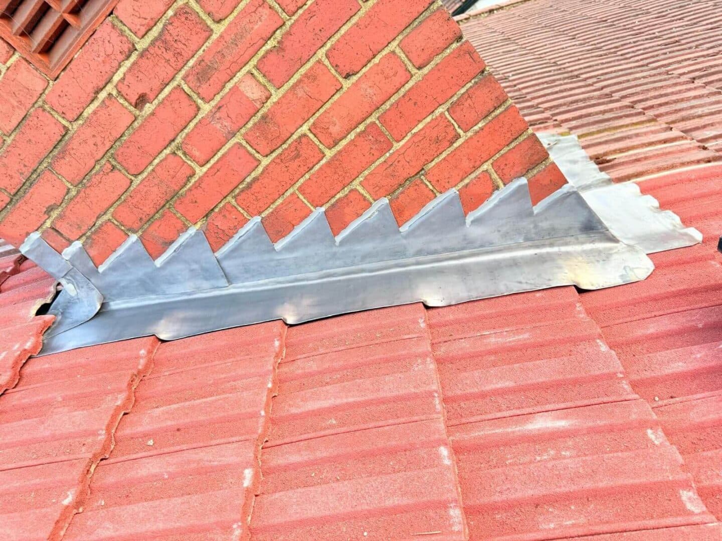 New stepped lead flashing and a lead apron around a brick chimney on a red tiled roof