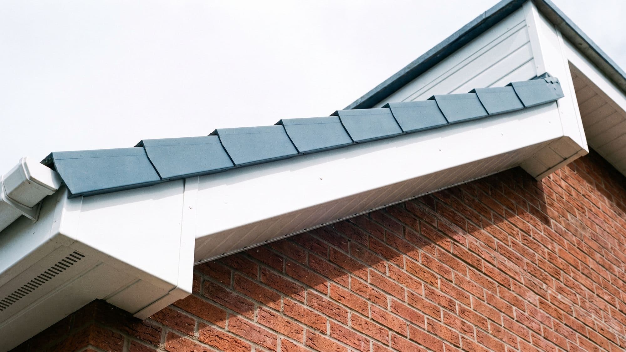 A long run of new white uPVC fascia and vented soffit beneath the edge of a slate roof